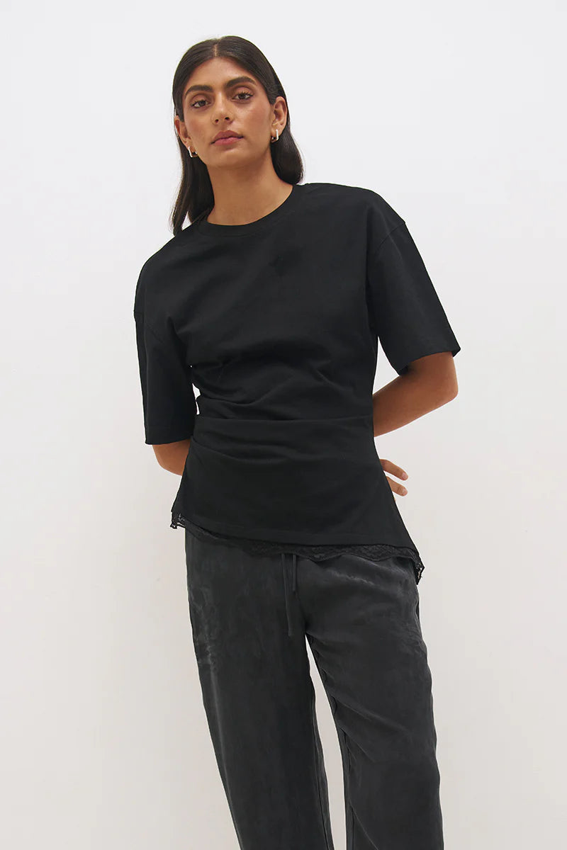 Mon Renn Liora T-Shirt in Black — cropped upper body shot showing crew neck, dropped shoulders, cinched waist seaming and delicate lace hem trim