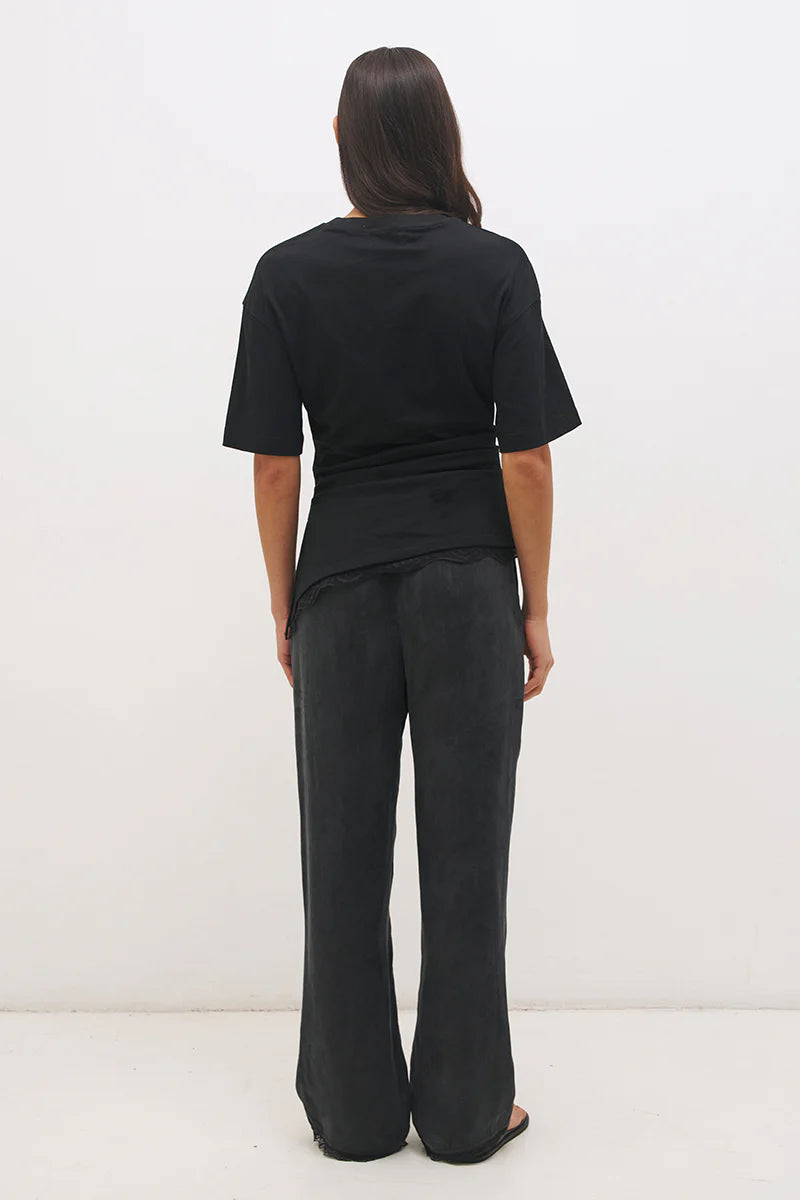 Mon Renn Liora T-Shirt in Black — back view showing clean silhouette with cinched waist and angled lace hem trim