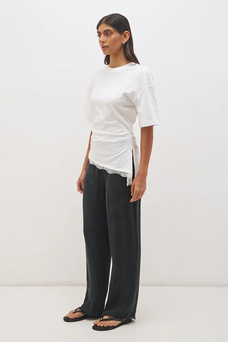 Mon Renn Liora T-Shirt in Off White — three-quarter side view showing cinched waist seaming, angled lace hem and asymmetric side split